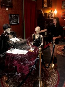 Mysterious skeletons sit around a table with a typewriter